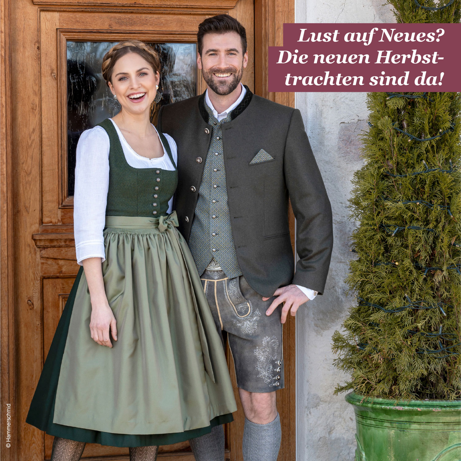 Teaser Paarbild Frau mit grünem Dirndl, weißer Bluse und Herr mit grünem Gilet und Sakko und Lederhose vor Eingangstür. Lust auf neues? Die neuen Herbsttrachten sind da