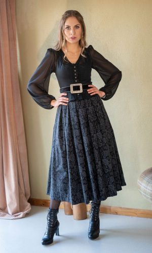 Dame in schwarzer Bluse mit langen Ärmeln und gemusterter schwarzer Trachtenrock