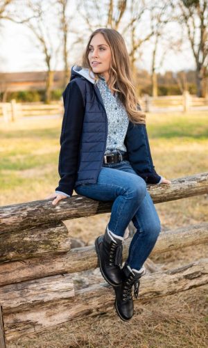 Dame mit Trachtenbluse, Jeanshose und blauer Weste