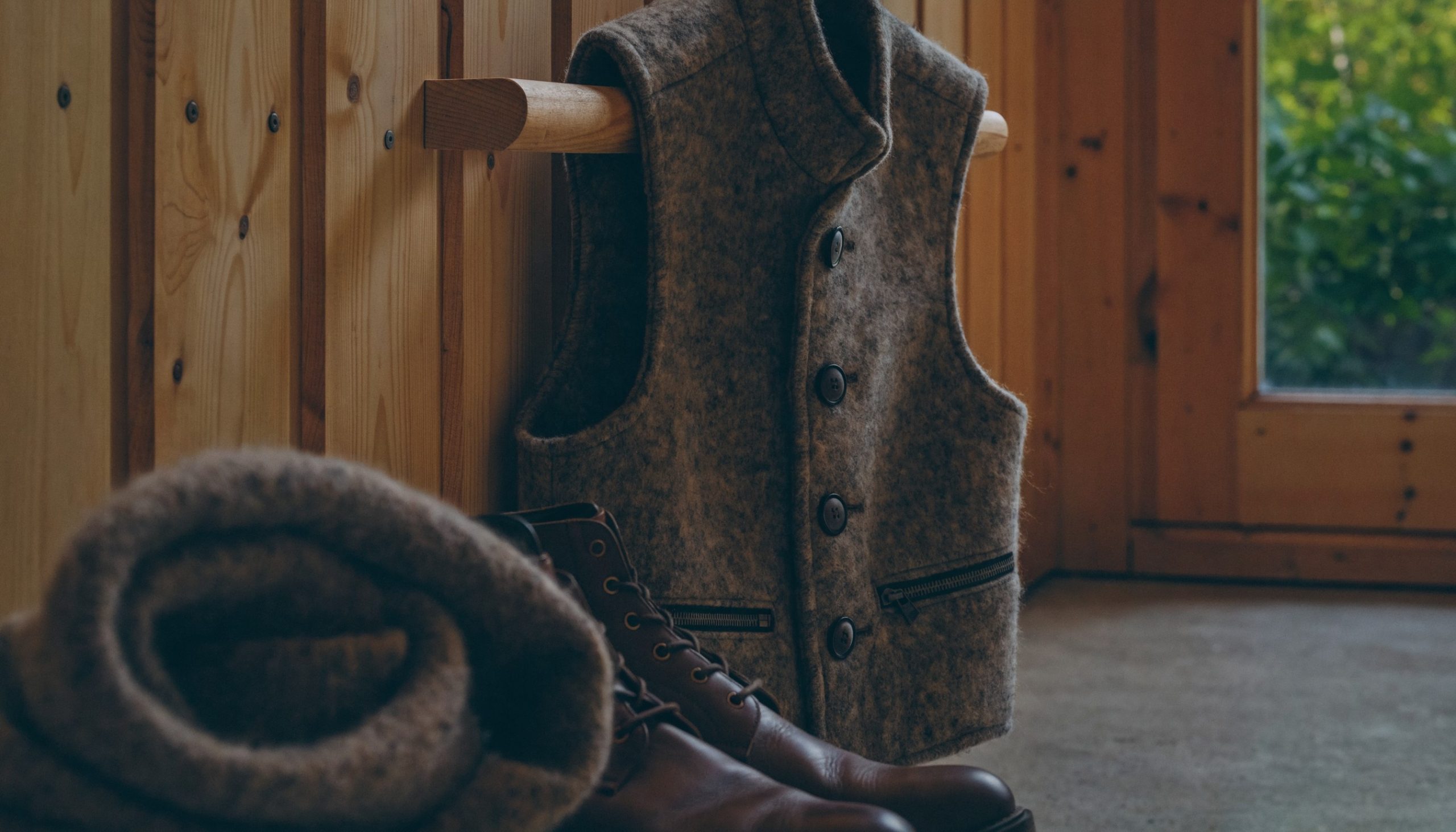 Lodenweste für Herren aus grau-braunem Loden mit Hornknöpfen an einer Garderobe aus Holz