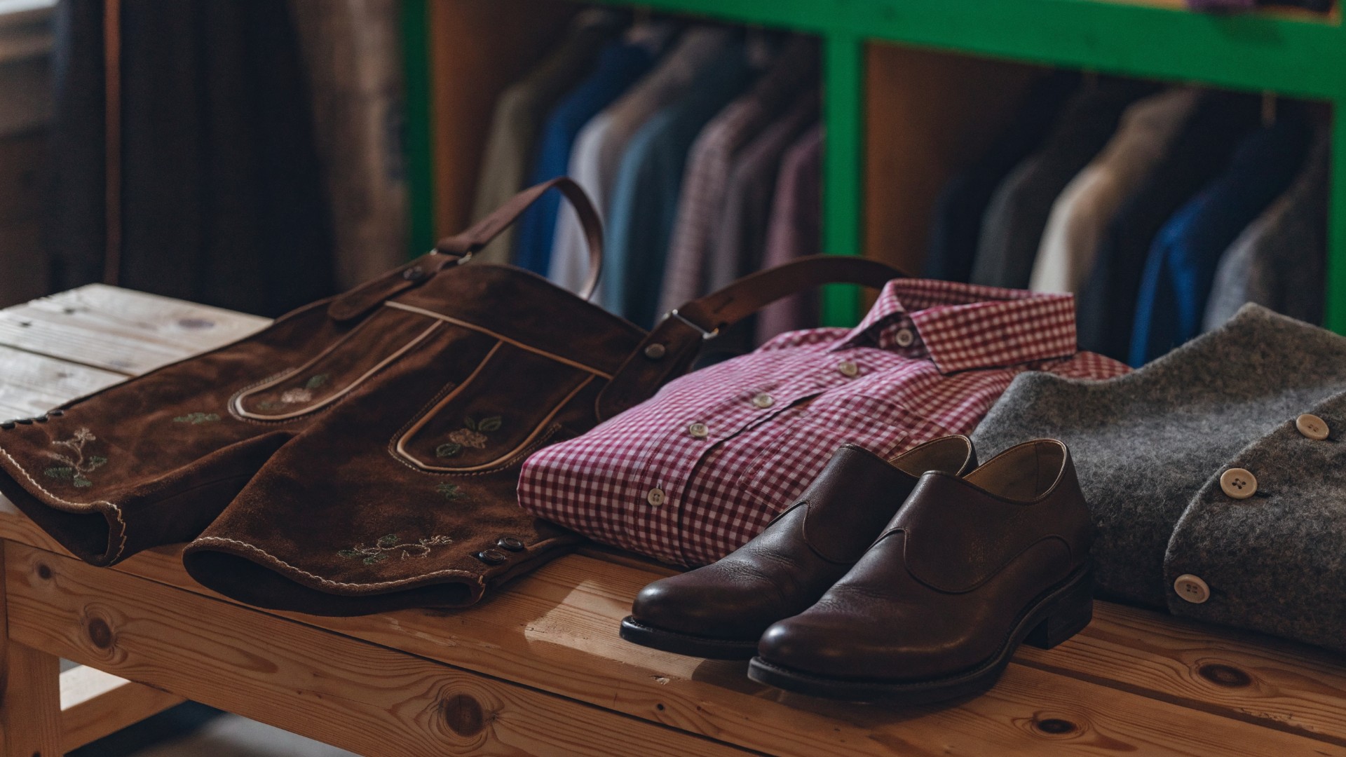 Tracht für Männer in Niederösterreich: Lederhose, kariertes Trachtenhemd, Lodengilet und Lederschuhe auf einer Holzbank